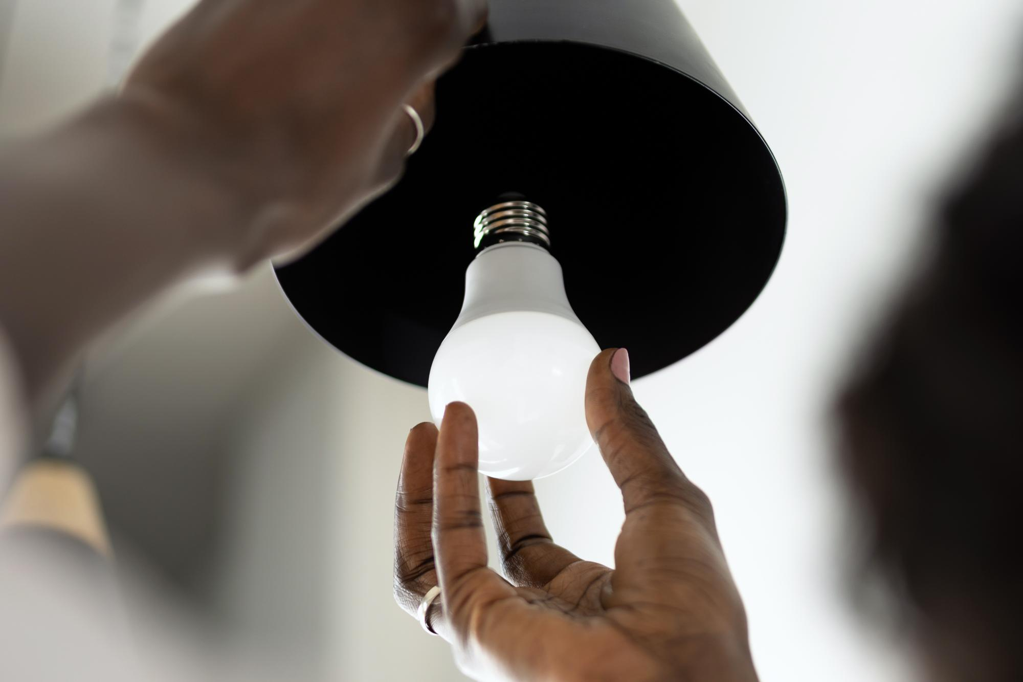 Primo piano di un dipendente intento a cambiare una lampadina